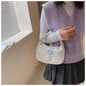 Detail einer weißen Nylontasche mit blauem Herz-Wal-Patch getragen von einem Model