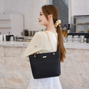 Minimalist black quilted tote bag with V-shaped texture and elegant gold chain strap