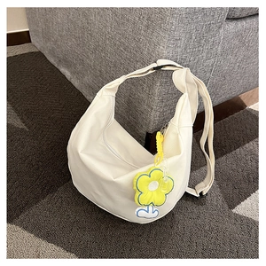 Gros plan d'un sac demi-lune en toile blanche avec un charmant détail de fleur jaune
