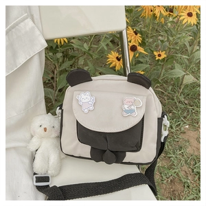 Detail of bunny ear flap crossbody bag with plush bear charm in a floral setting