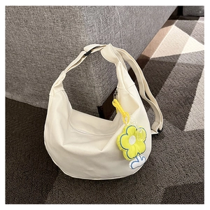 Détail du sac bandoulière en toile blanc cassé avec pendentif fleur jaune vif