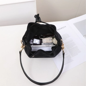 Large capacity black suede bucket bag with gold hardware shown with daily essentials