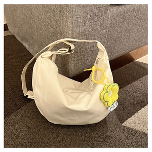Détail d'un sac demi-lune en toile blanc crème avec un accessoire de charme fleur jaune