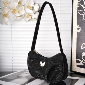Detail of black velvet pleated shoulder bag with gold butterfly clasp and orchid background