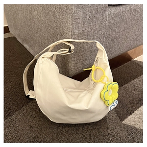 Détail du sac demi-lune en toile blanc crème avec breloque tournesol jaune