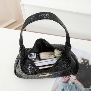Sac hobo noir tressé montrant l'espace intérieur avec téléphone et accessoires