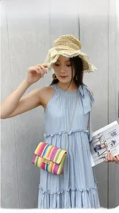 Detail of colorful woven crossbody bag with gold chain and metal buckle on summer outfit