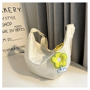 Détail du sac bandoulière demi-lune en toile blanche avec breloque tournesol et sangle large