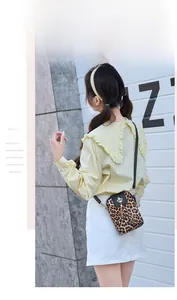 Detail of leopard print crossbody phone bag with gold crown buckle and black leather flap