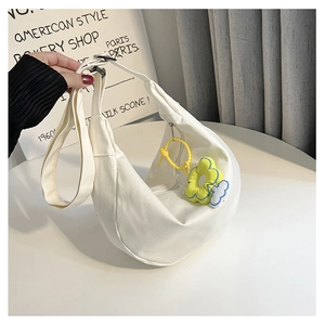 Détail d'un sac bandoulière en toile blanche avec sangle réglable et pendentif fleur jaune