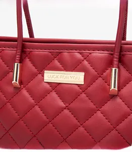 Dettaglio ravvicinato della borsa in pelle trapuntata rossa con ferramenta in oro