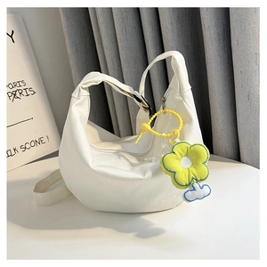 Détail du sac à bandoulière blanc en forme de croissant avec un pendentif fleur jaune vif