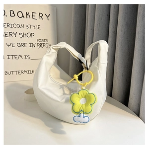 Détail du sac hobo blanc à texture tissée et breloque fleur jaune en accessoire