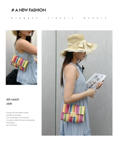 Close-up of rainbow straw woven crossbody bag with gold chain strap and metal lock detail