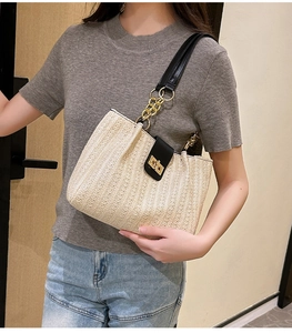 Detail of straw bucket bag featuring cream woven texture and black leather flap with gold lock