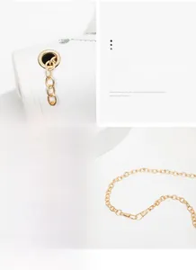 Detailed macro view of high-quality gold chain hardware on a white embroidered crossbody bag