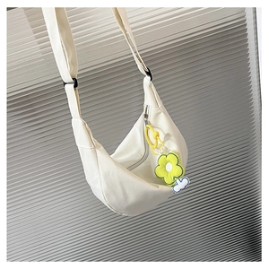 Détail du sac bandoulière demi-lune en toile blanche avec charm fleur jaune et sangle