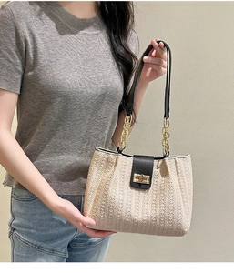 Detail of woven straw tote bag with black leather flap and gold buckle closure