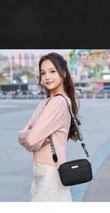 Detail of black quilted camera bag with elegant gold trim and wide lettered shoulder strap