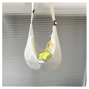 Détail du sac demi-lune en toile blanche avec breloque fleur jaune et large bandoulière