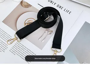 Adjustable black nylon shoulder strap with gold metal buckles on a stylish magazine