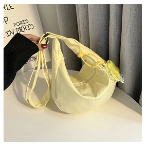 Détail du sac demi-lune en toile jaune pâle avec charme floral et fermeture éclair