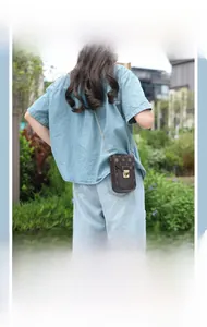 Detail of vintage monogram mobile phone bag with golden chain strap on a model