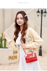Detail of red quilted crossbody bag with silk scarf handle and gold twist lock clasp
