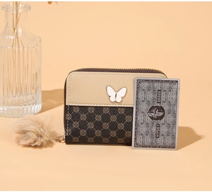 Detail of mini zipper wallet in beige and brown with floral pattern and fuzzy pom pom charm