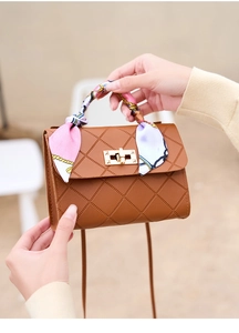 Detailed shot of brown quilted crossbody bag with silk scarf handle and gold twist lock