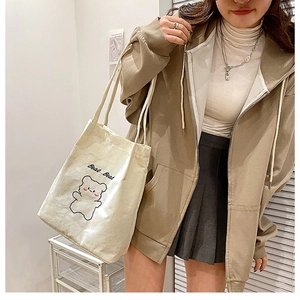 Dettaglio della borsa tote in velluto a coste crema con ricamo a forma di orso