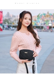 Detail of black quilted crossbody bag with golden hardware and wide fabric strap