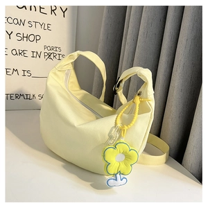 Détail du sac croissant en toile jaune clair avec breloque fleur et bandoulière large