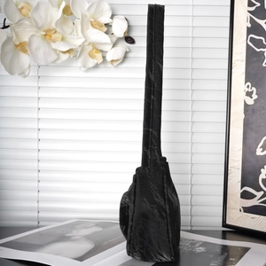 Detail of black pleated fabric texture on a minimalist shoulder bag with smooth lighting