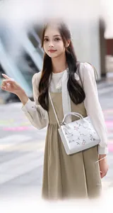 White mini square bag with floral embroidery held by a model in a beige dress outdoors