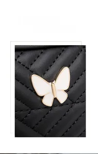 Macro shot of quilted black faux leather cross-body bag with gold butterfly metal detail
