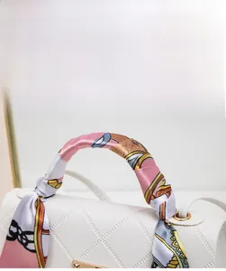 Detail of colorful floral silk scarf wrapped on white quilted handbag handle