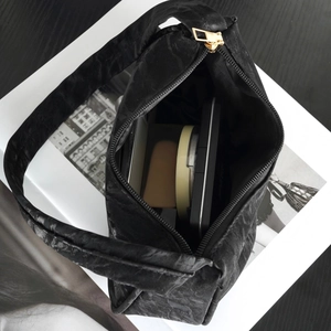 Chic black textured hobo bag with gold zipper showing interior cosmetic storage space