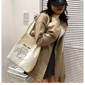 Dettaglio della borsa tote in velluto a coste bianco crema con orsetto minimalista