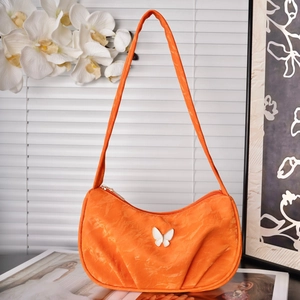 Detail of orange ruffled shoulder bag with white butterfly charm and marble texture fabric