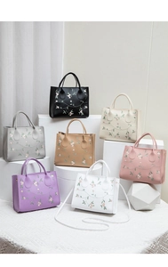 Detailed display of seven colored handbags featuring intricate floral embroidery textures