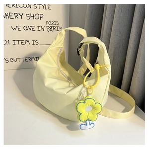 Détail du sac croissant jaune en toile avec breloque fleur et bandoulière en nylon