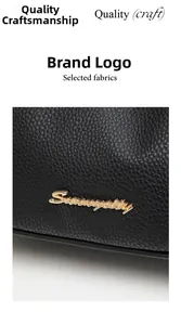 Detailed macro view of black lychee grain leather handbag with gold metal logo hardware