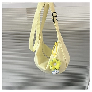 Détail du sac croissant en toile jaune pâle avec breloque fleur et bandoulière réglable