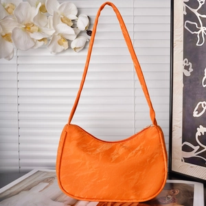 Close-up of vibrant orange pleated shoulder bag with smooth texture and zipper closure