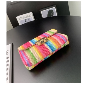 Detail of colorful woven straw bag with rainbow stripes and gold rectangular metal clasp