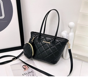 Detail of black quilted tote bag with gold hardware and removable round coin purse charm