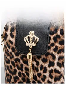 Macro shot of leopard print bag featuring a gold crown emblem and metallic tassels