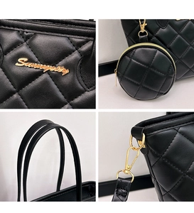 Detail view of black quilted tote bag with gold logo, charms and hardware details