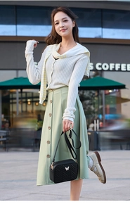 Outdoor street style view of a black quilted crossbody bag with butterfly embroidery detail